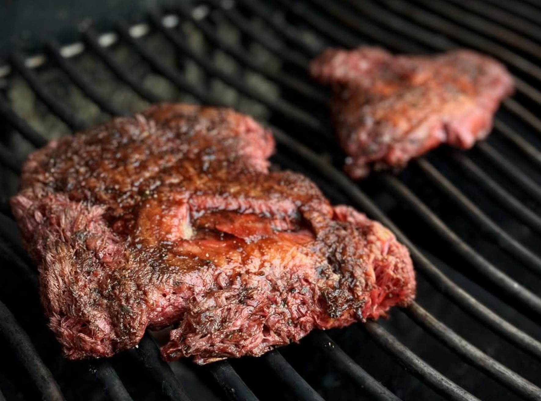 Two seared lion's mane steaks on a hot grill, showing the medium-rare beetroot bleed inside